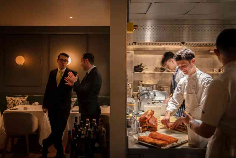 Una delgada pared divisoria muestra el contraste entre la atmósfera tranquila en el comedor del restaurante Trinity con una estrella Michelin de Adam Byatt en Clapham, al sur de Londres, y los chefs ocupados en la cocina